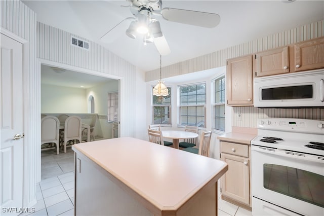 kitchen with light brown cabinets, decorative light fixtures, white appliances, a kitchen island, and vaulted ceiling