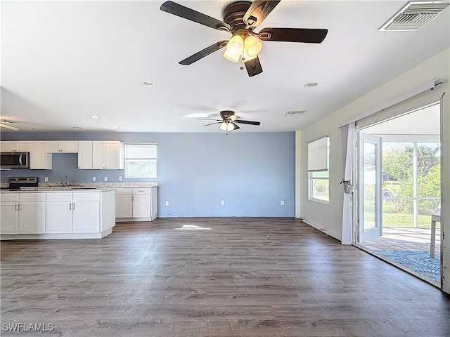 kitchen with stainless steel appliances, sink, hardwood / wood-style floors, white cabinetry, and ceiling fan