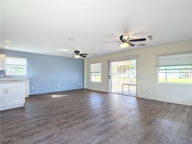 unfurnished living room featuring ceiling fan, a healthy amount of sunlight, and dark hardwood / wood-style floors