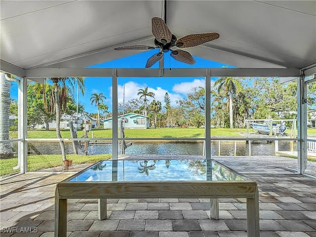 unfurnished sunroom featuring a water view, ceiling fan, and vaulted ceiling