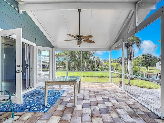 unfurnished sunroom featuring lofted ceiling, a water view, and ceiling fan