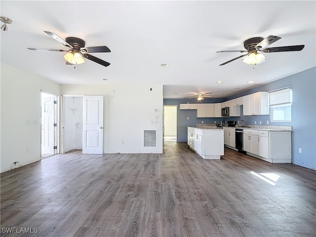 kitchen with a kitchen island, sink, stainless steel dishwasher, white cabinets, and light hardwood / wood-style floors