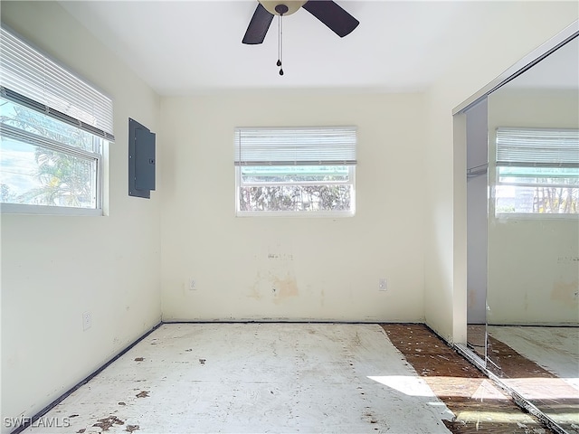 empty room featuring electric panel, ceiling fan, and plenty of natural light