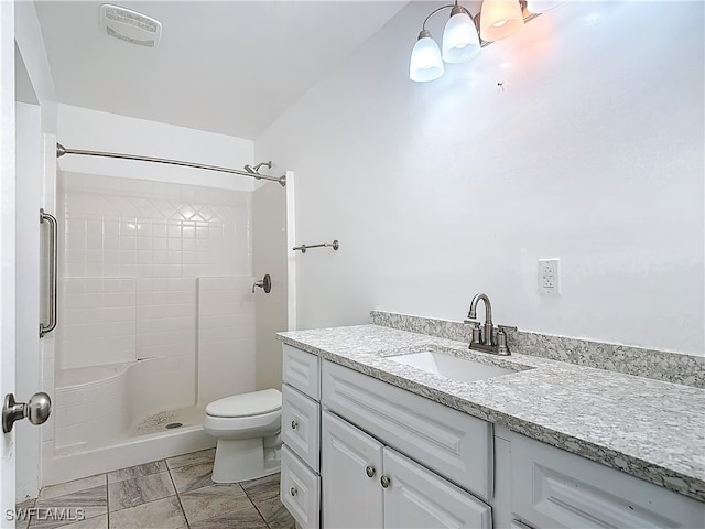 bathroom with vanity, toilet, and tiled shower