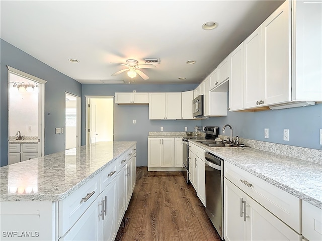 kitchen with white cabinets, dark hardwood / wood-style flooring, light stone countertops, sink, and stainless steel appliances