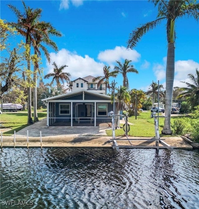 back of house with a yard, a water view, and a sunroom