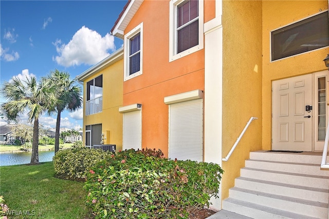 view of exterior entry with a yard and a water view