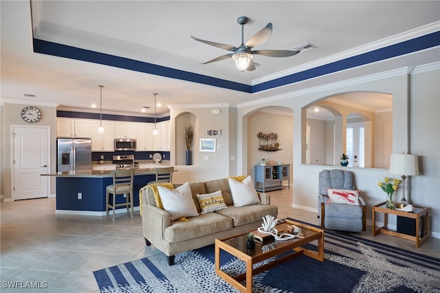 living room with ceiling fan, crown molding, and light tile patterned floors