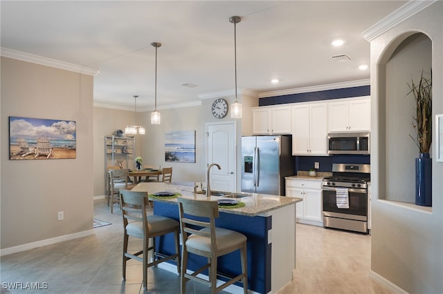 kitchen with stainless steel appliances, white cabinets, sink, an island with sink, and pendant lighting