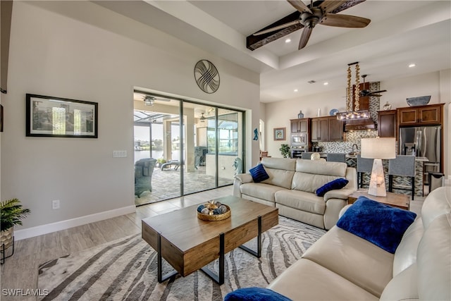 living room with beam ceiling, sink, light hardwood / wood-style flooring, and ceiling fan