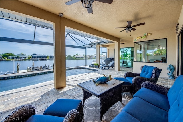 view of patio / terrace featuring a lanai, a water view, and ceiling fan