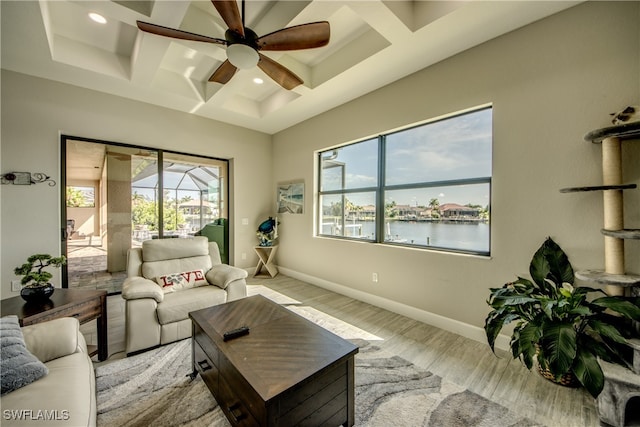 living room featuring a water view, light hardwood / wood-style floors, coffered ceiling, and beam ceiling