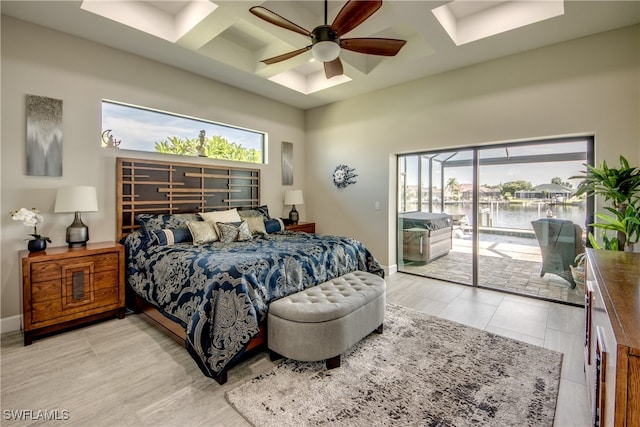 bedroom featuring a water view, multiple windows, access to exterior, and ceiling fan