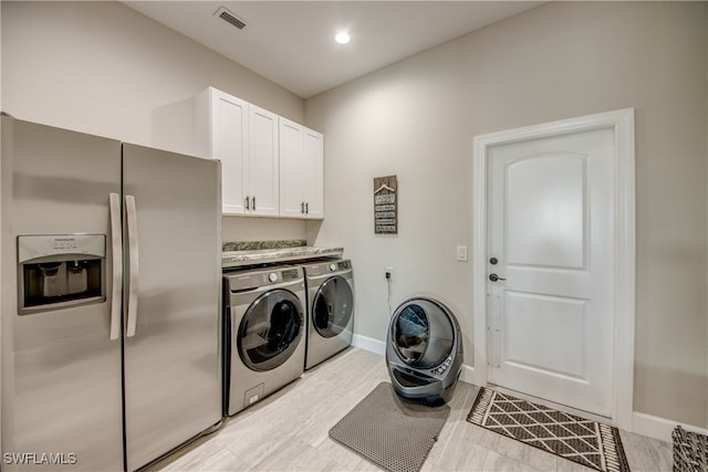 laundry area featuring cabinets, light hardwood / wood-style flooring, and separate washer and dryer