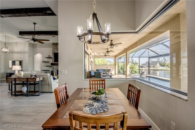 dining space featuring a water view, beam ceiling, and ceiling fan