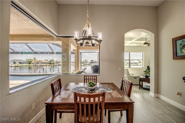 dining space featuring ceiling fan, wood-type flooring, beamed ceiling, coffered ceiling, and a water view