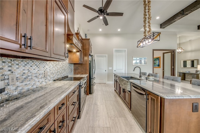 kitchen with appliances with stainless steel finishes, light stone countertops, sink, and hanging light fixtures