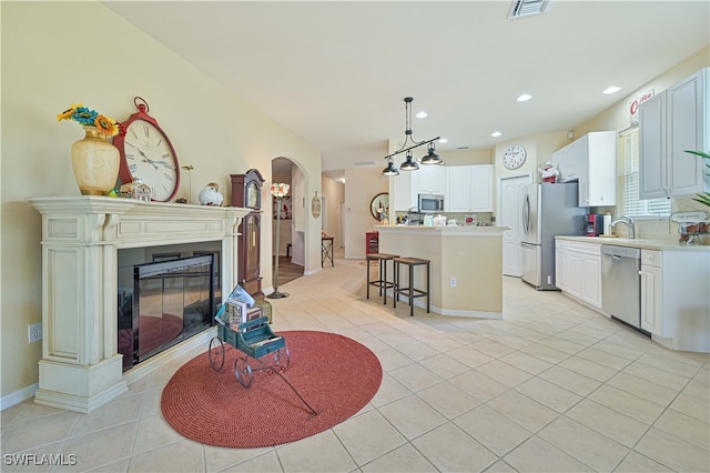 interior space featuring a center island, decorative light fixtures, a kitchen bar, light tile patterned floors, and appliances with stainless steel finishes