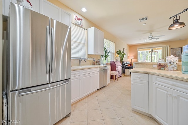 kitchen with appliances with stainless steel finishes, sink, decorative light fixtures, white cabinetry, and light tile patterned flooring