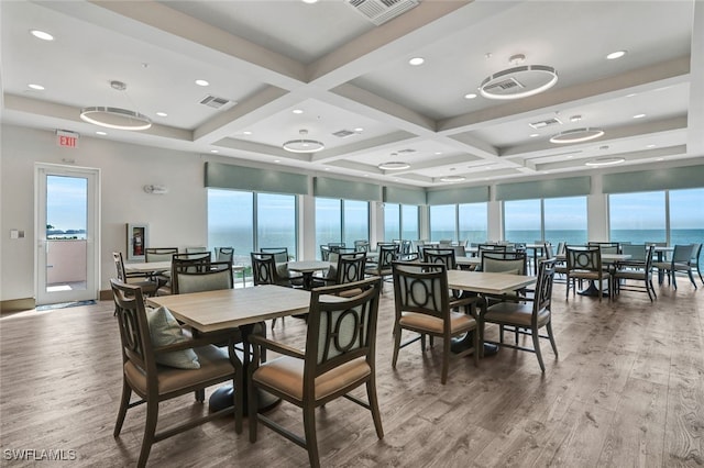 dining space with beam ceiling, hardwood / wood-style floors, a water view, and coffered ceiling