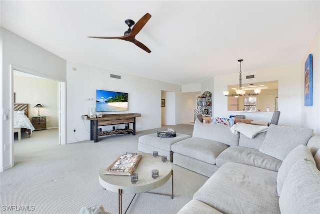 carpeted living room with ceiling fan with notable chandelier