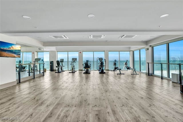 gym with hardwood / wood-style floors, a water view, and plenty of natural light