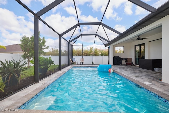 view of pool featuring glass enclosure, a patio, and ceiling fan