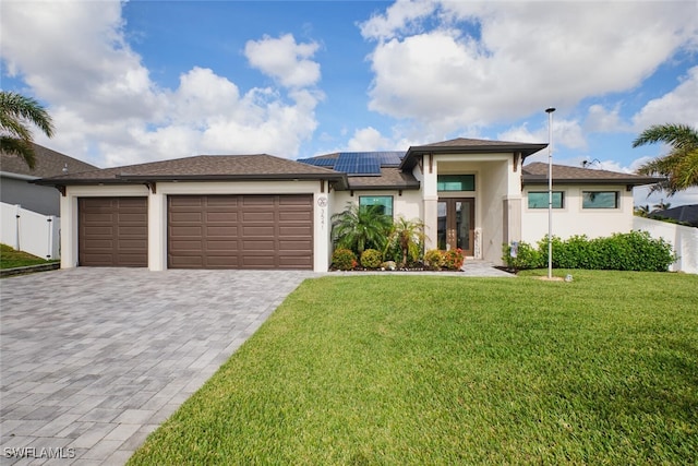 prairie-style house featuring a garage, solar panels, and a front yard