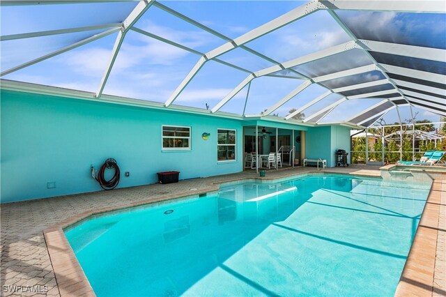 view of pool with glass enclosure, ceiling fan, and a patio area