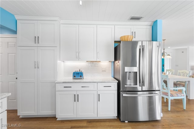 kitchen with light hardwood / wood-style floors, stainless steel fridge, and white cabinetry