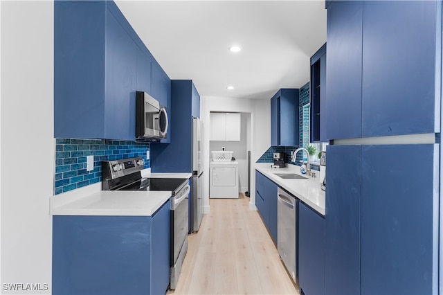 kitchen featuring stainless steel appliances, sink, blue cabinetry, washer / dryer, and light hardwood / wood-style floors