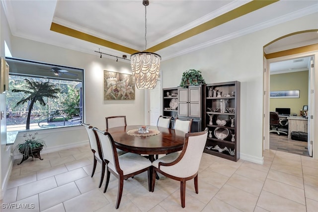 dining space with ornamental molding, a notable chandelier, light tile patterned flooring, and a tray ceiling