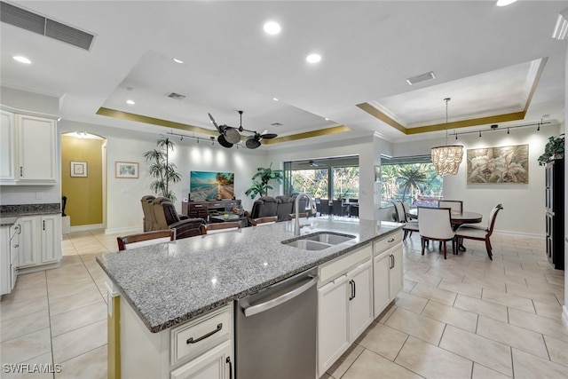 kitchen featuring stainless steel dishwasher, a tray ceiling, sink, and a kitchen island with sink