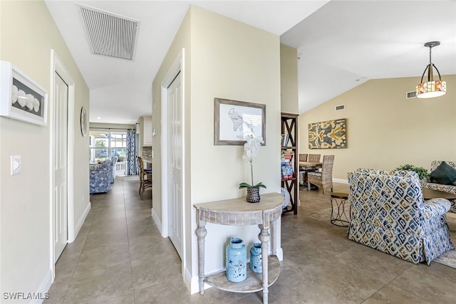 hall with lofted ceiling and light tile patterned flooring