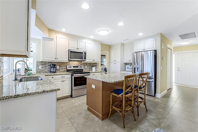 kitchen featuring stainless steel appliances, white cabinets, sink, and a kitchen island