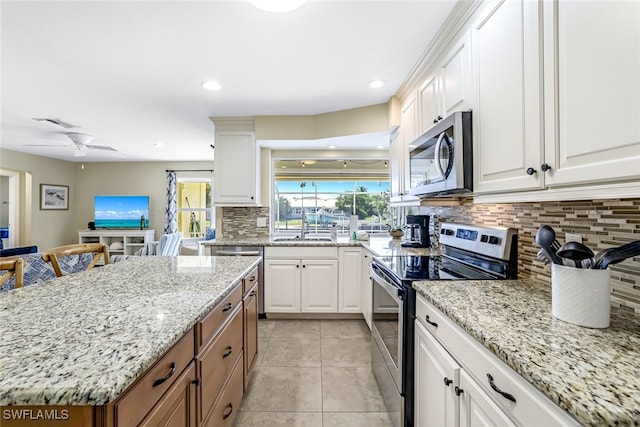 kitchen with white cabinetry, stainless steel appliances, light stone counters, and backsplash