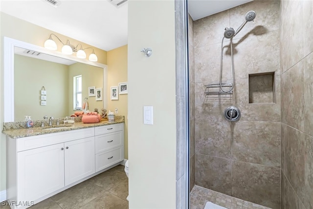 bathroom with tile patterned flooring, vanity, and tiled shower