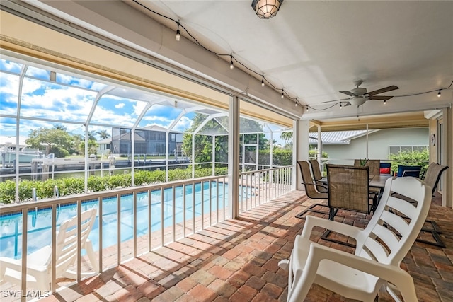 view of swimming pool with a patio, glass enclosure, and ceiling fan