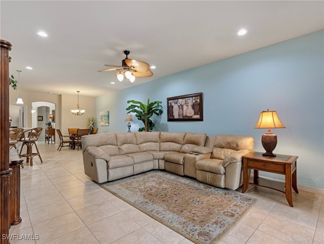 tiled living room with ceiling fan with notable chandelier