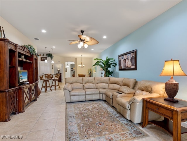 tiled living room featuring ceiling fan with notable chandelier