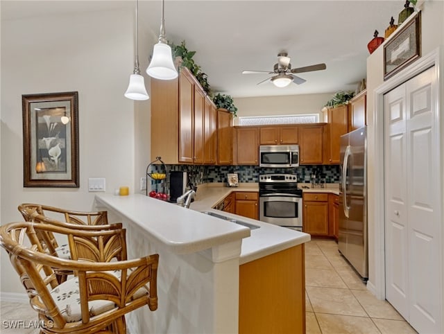 kitchen featuring tasteful backsplash, kitchen peninsula, stainless steel appliances, decorative light fixtures, and light tile patterned floors