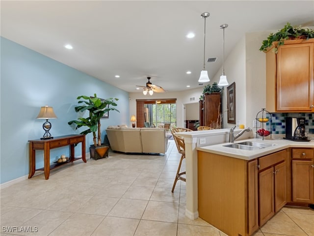 kitchen featuring sink, backsplash, ceiling fan, pendant lighting, and a breakfast bar