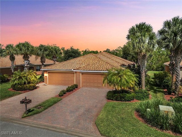 mediterranean / spanish-style home featuring a garage and a lawn