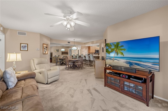 living room with ceiling fan, light colored carpet, and a textured ceiling