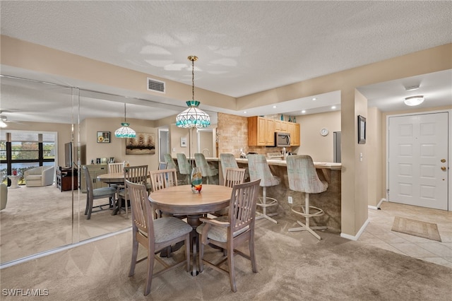 carpeted dining space with ceiling fan and a textured ceiling