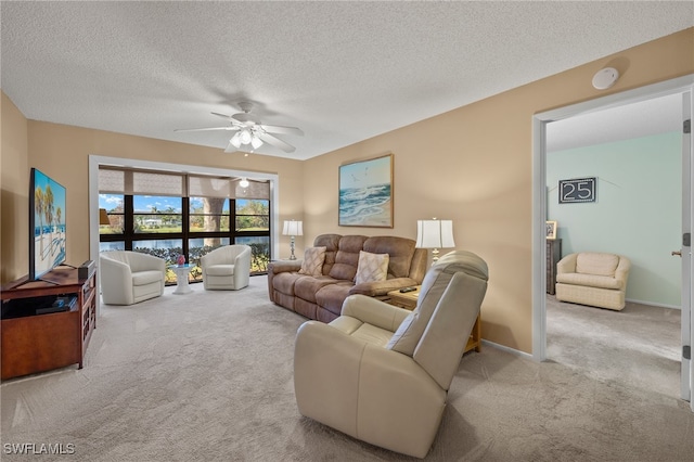 living room featuring light carpet, a textured ceiling, and ceiling fan