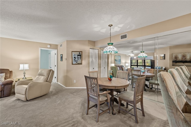 carpeted dining room featuring ceiling fan and a textured ceiling