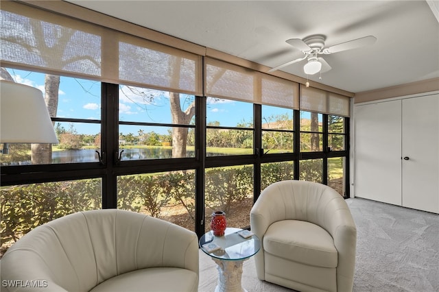 sunroom featuring ceiling fan and a water view