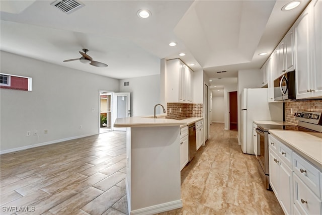 kitchen featuring ceiling fan, tasteful backsplash, kitchen peninsula, white cabinets, and appliances with stainless steel finishes