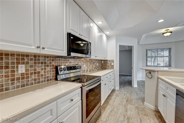 kitchen featuring tasteful backsplash, white cabinets, vaulted ceiling, and appliances with stainless steel finishes